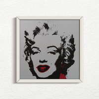 an image of an artwork titled 'golden marilyn 36' by andy warhol in a white frame. the artwork features a stencilled image of marilyn monroe's face in black on a grey background, with red pops of colour around the mouth and to the right of the face. this is a sunday b morning print