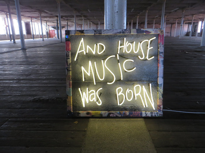 Explore the unique fusion of art and music with Tony Spink's Acid House Music Was Born. This one-of-a-kind artwork features white neon on a textured faux concrete backing panel, adorned with a collage frame depicting the iconic 1987/1988 acid house scene. Measuring 69 x 76 cm, this original masterpiece is a vibrant addition to any collection. Elevate your space with this distinctive neon artwork capturing the essence of a bygone musical era