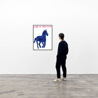 photo of a david shrigley art print in a black frame, hanging on a white wall in a viewing space, with a single spectator viewing the piece from the right. the print features a large, galloping dark blue horse painted in david shrigley's signature childlike style. david shrigley prints david shrigley art david shrigley posters