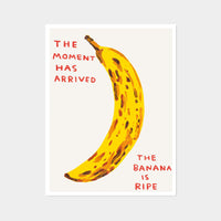 this is an image of a david shrigley artwork titled 'the moment has arrived'. the artwork features a large painting of a brown spotted banana with handwritten text either side stating 'the moment has arrived', 'the banana is ripe'. this is a david shrigley print for sale