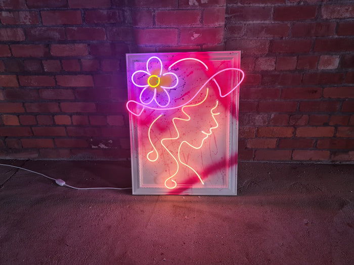 Add a burst of color to your space with Tony Spink's Doris. This one-of-a-kind artwork features multicoloured neon on a wooden backing painted white, presented in an ornate frame with splashes of vibrant hues. Measuring 61 x 82 cm, this original masterpiece is a unique fusion of neon art and ornate design. Elevate your space with this distinctive neon artwork, a lively addition to any art collection.