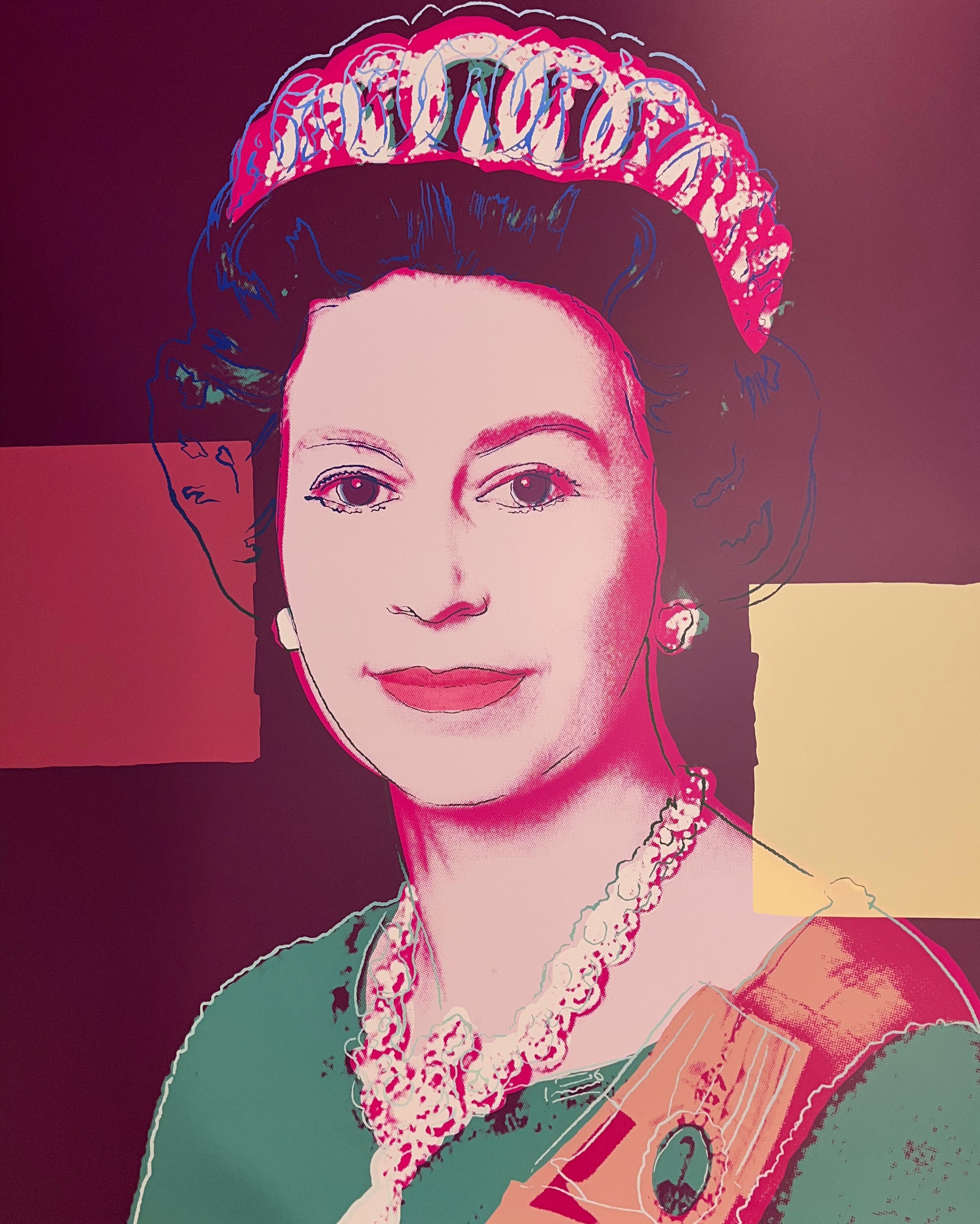 an image of an artwork by andy warhol titled 335 queen elizabeth II. the image features a young queen elizabeth in a colourised pop art style, with green and orange clothing and a pink-toned face. the background is mauve and there are two square blocks of colour, one in red on the left, and one yellow on the right. the image is a screenprint by sunday b morning