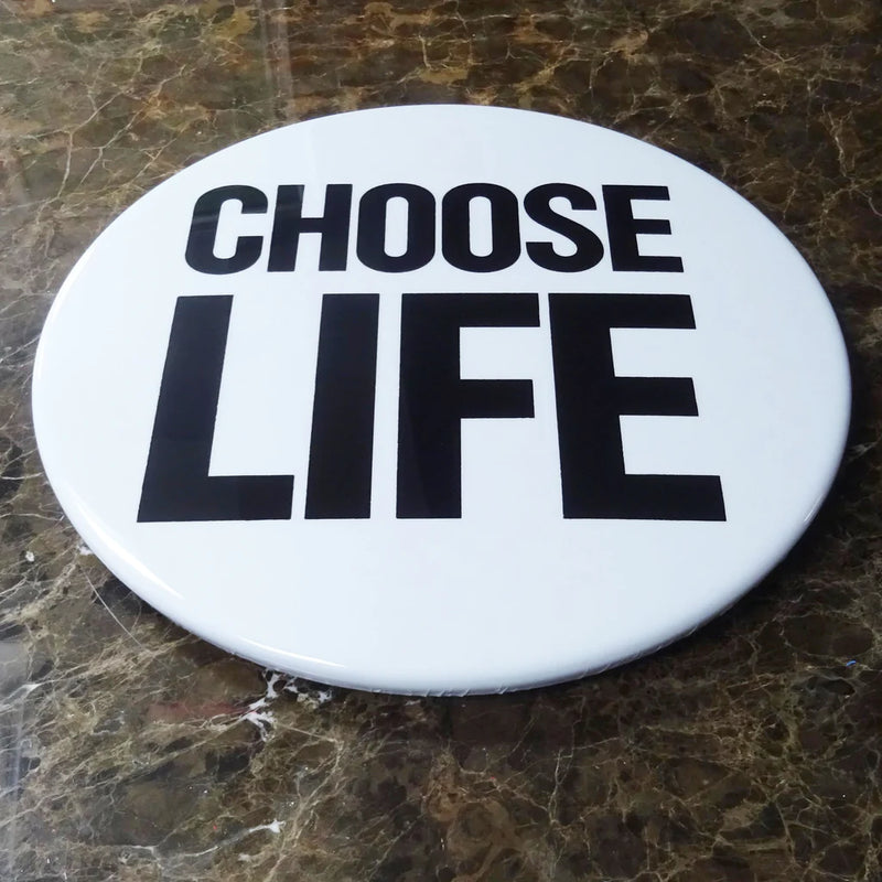 Choose Life Giant 3d Badge by Tape Deck Art resting against a wall 