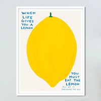 An image of an artwork by David Shrigley titled 'When Life Gives You A Lemon' in a white frame. The piece features a large, cartoon-like depiction of a lemon, with text at the top right stating 'WHEN LIFE GIVES YOU A LEMON', and in the bottom right continuing 'YOU MUST EAT THE LEMON', 'ALL OF IT', 'INCLUDING THE SKIN'. This is a David Shrigley Poster or Print